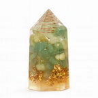 Crystal tower with green stones and gold flakes on a white background