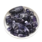 Purple crystals in a white bowl on a white background