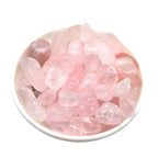 Pink crystal stones in a white bowl on a white background