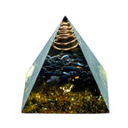 Pyramid-shaped crystal with gold and black stones on a white background