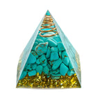 Pyramid-shaped container with turquoise stones and a gold spiral on a white background