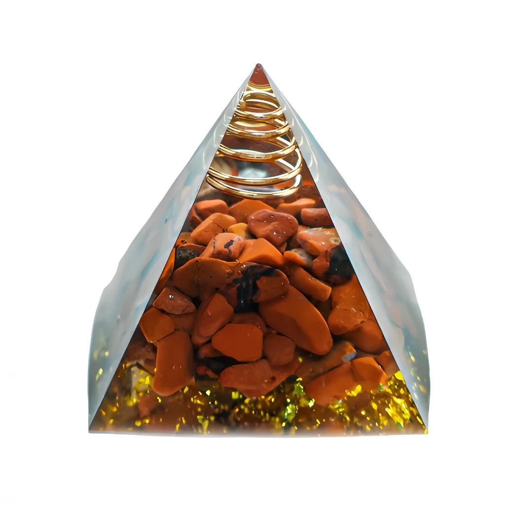 Pyramid-shaped orgone crystal with orange stones and gold coils on a white background