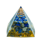 Pyramid-shaped crystal orgone with blue stones and gold elements on a white background