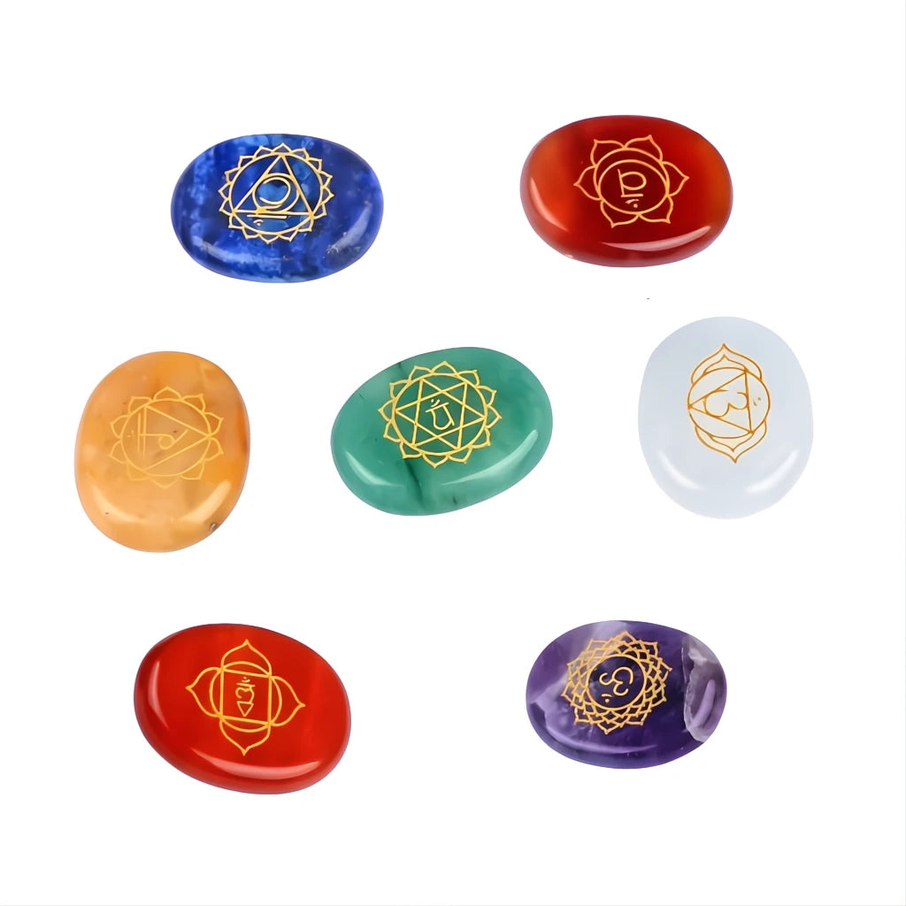 Set of seven chakra stones with symbolic designs on a white background
