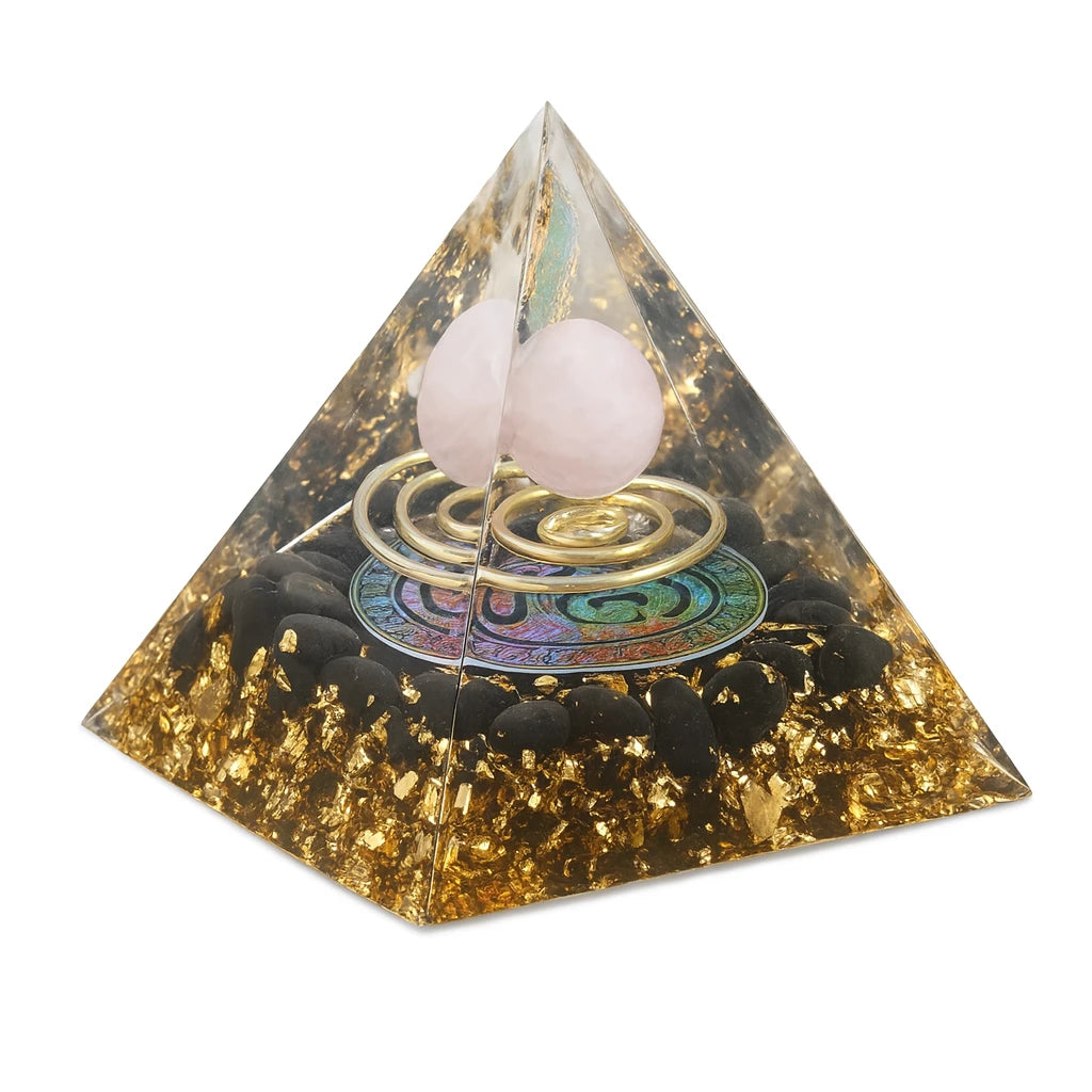 Pyramid-shaped crystal with pink balls and gold spiral on a white background