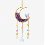 Decorative hanging ornament with a crescent moon, stars, and purple crystals on a white background