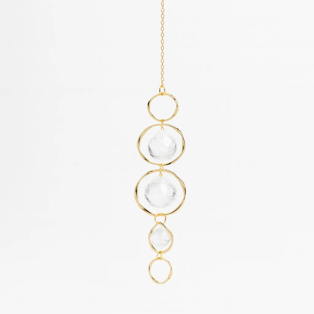 Gold necklace with clear glass beads on a light gray background