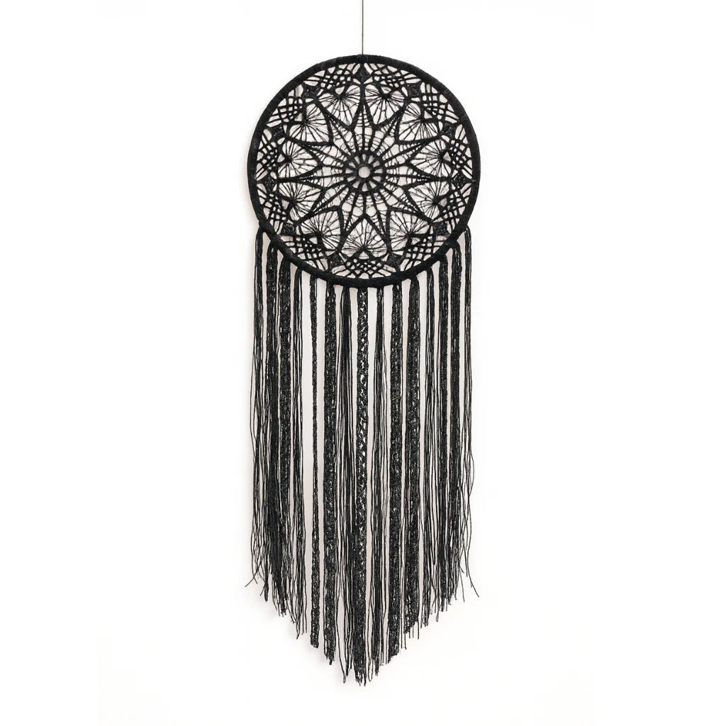 Black dreamcatcher with intricate design and hanging fringes on a white background