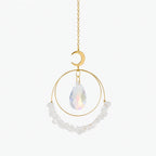 Decorative hanging ornament with gold chain, moon-shaped pendant, teardrop crystal, and white beads on a white background.