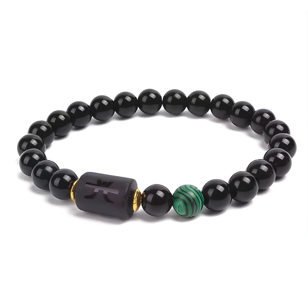 Black beaded bracelet with a unique charm and green bead on a white background