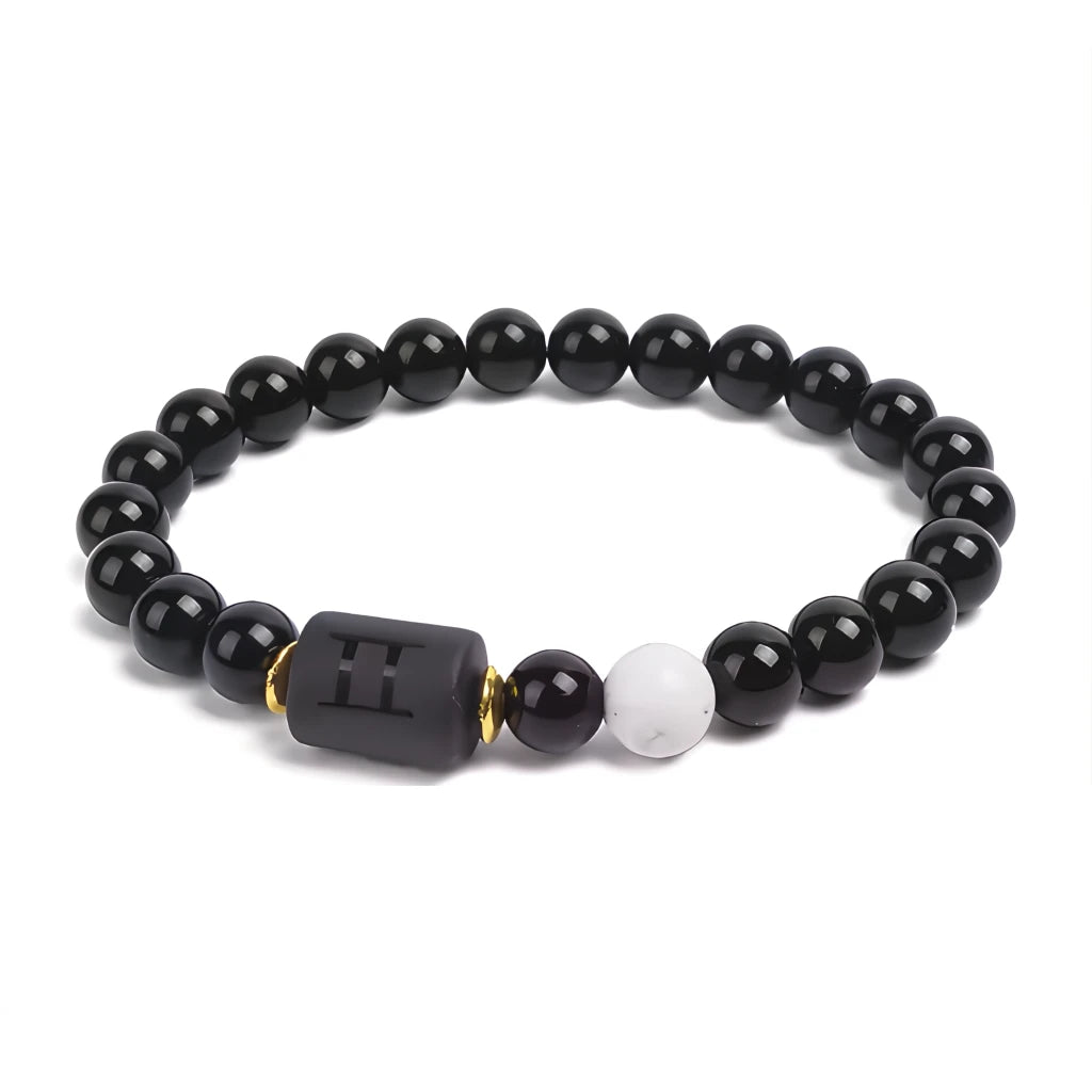 Black beaded bracelet with a central black square bead and one white bead on a white background