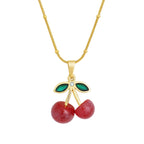 Gold necklace with cherry pendant on a white background