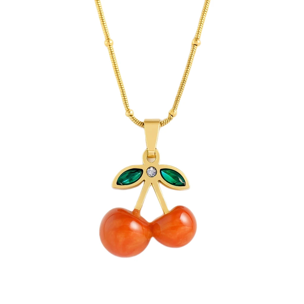 Gold necklace with an orange cherry pendant on a white background