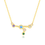 Gold necklace with a zodiac sign pendant featuring colorful gemstones on a white background