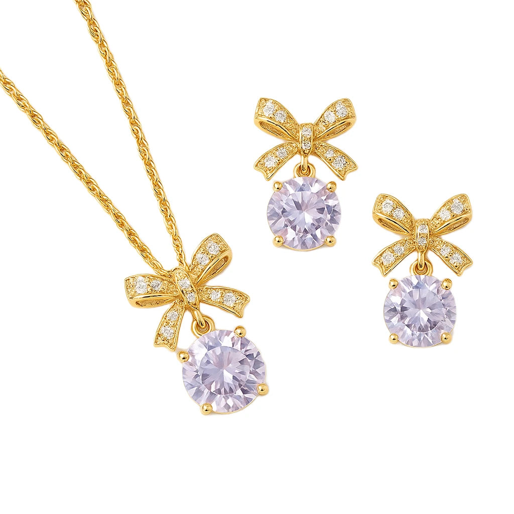 Gold jewelry set with bow designs and purple gemstones on a white background