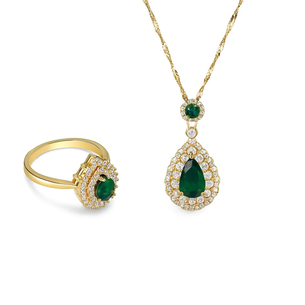 Gold necklace with emerald pendant and matching ring on a white background