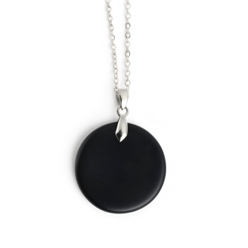 Black circular pendant on a silver chain against a white background